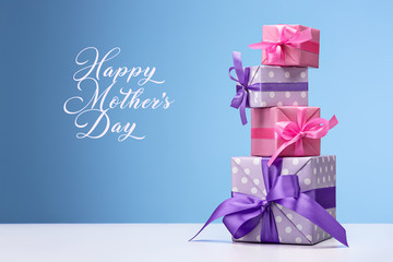 Gifts for mom. Greeting card, frame, banner. Set of gifts in boxes decorated with satin ribbon on blue background. Copy space.