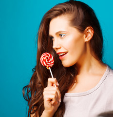 young pretty brunette woman posing happy cheerful on blue background with candy, lifestyle people concept