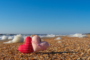 Image of a soft toy in the shape of a heart on the beach.