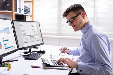 Businessman Calculating Invoice In Office
