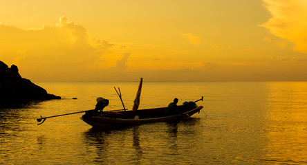 The fishing boat is parked in the sea during the sun falling.
