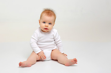 Charming blue-eyed baby 9 months old on white background in white clothes