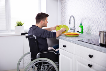 Handicapped Man Cleaning Dishes In Kitchen