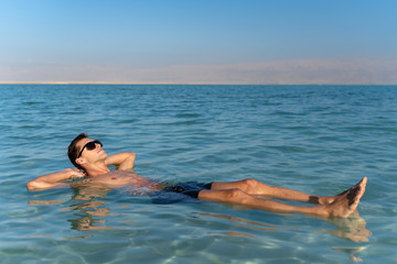 young man floating on the water surface of the dead sea