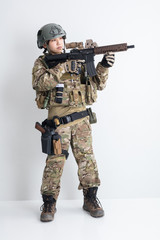 白背景に迷彩服を全身着たかっこいい女の子が銃を持っているサバイバルゲームサバゲー体験 