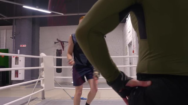 Professional workout with personal trainer, fighter is skipping on jumping rope on ringside crossing his hands.