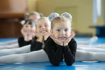 Little girls gymnasts sit on the splits. Children do physical exercise. Young ballerinas.. Training...