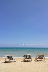 Three folding beach chairs on the beach with sea and bright sky in the background at Koh Mak in Trat, Thailand. Seasonal Vacation. Background with copy space.
