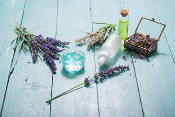 cream, shampoo, perfume product samples with lavender on old blue wood table background