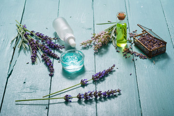 cream, shampoo, perfume product samples with lavender on old blue wood table background