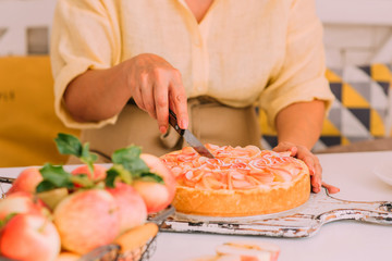 Sweet homemade pie ready to eating. Whole apple pie and a piece is taken out with a cake server. Tasty apple cake served for dessert. Traditional apple pie with cinnamon.