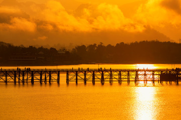 Fototapeta premium Golden morning light. Mon Bridge is the long wooden bridge. Official name is Attanusorn Bridge. Is the route of the villagers cross to Mon village, Sangkhla Buri, Kanchanaburi, Thailand 24 Jan 2019