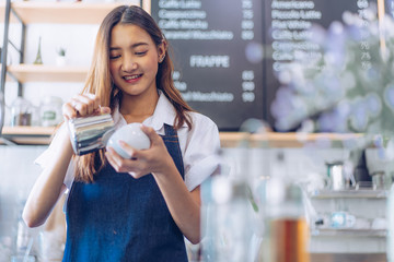 Pretty young asian waitress standing arms crossed in cafeteria.Coffee Business owner Concept.  barista in apron smiling at camera in coffee shop counter