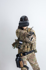 白背景に迷彩服を着た女の子がVRゴーグルをつけて銃でサバゲーをしている姿仮想現実
