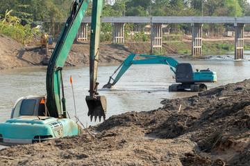 Backhoes digging sand with shovels .from the River © kaiskynet
