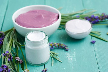 cosmetic creams and lavender flowers on blue wooden table
