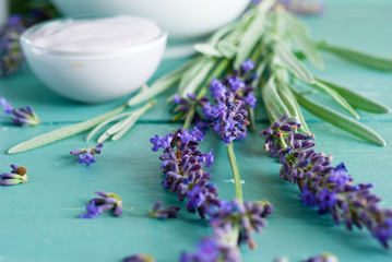 cosmetic creams and lavender flowers on blue wooden table