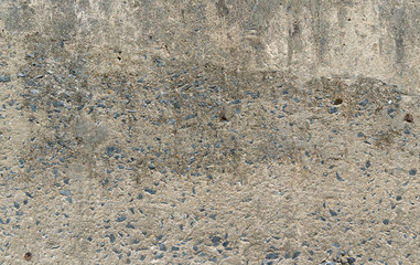 Old grey outdoor concrete wall texture background with broken plaster showing small stone inside 