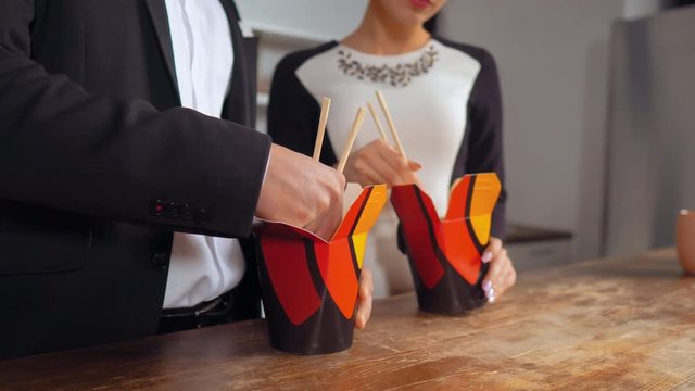 Two collagues eat Chinese noodles. Female and male workers eating Asian cuisine.