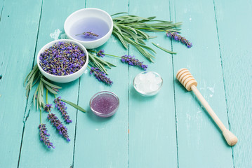 cup of lavender tea with a pile of flowers, syrup, candy sugar and dipper on blue wood table