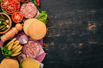 Raw burger Cooking a burger with meat. On a black wooden background. Top view. Free copy space.