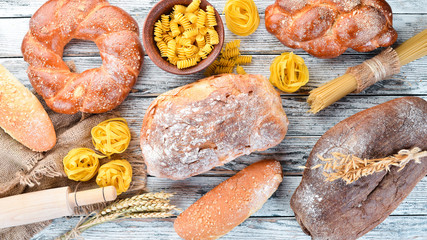 Gluten free food. Various pasta, bread, snacks and flour on a white wooden background. Top view....