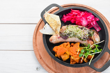 Baked sausages, sweet potatoes and cabbage. In the plate. Top view. Free space for your text. Rustic style.