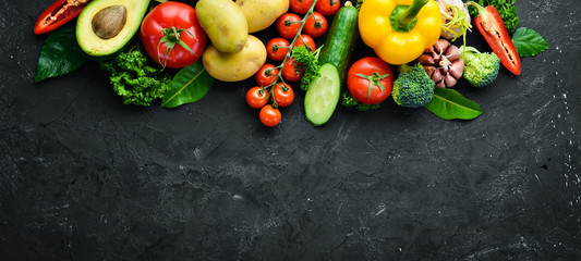 Fresh vegetables on a black background. Avocados, tomatoes, potatoes, paprika, citrus. Top view. Free space for your text.