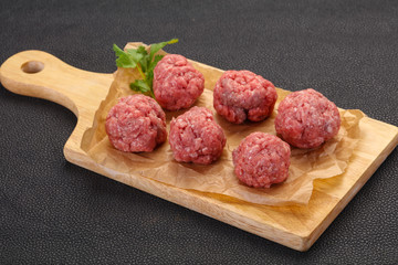 Raw meatball over wooden background