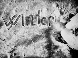 White figure skates in the snow. Snow on ice skates. The word winter written on the snow. Winter...