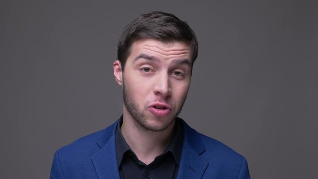 Closeup shoot of young handsome caucasian man talking on camera with background isolated on gray