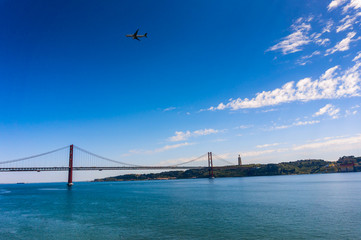 Cityscape with 25 April Bridge over the Tagus river and airplane in Lisbon