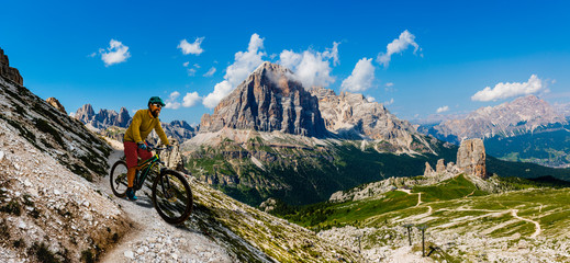 Tourist cycling in Cortina d'Ampezzo, stunning Cinque Torri and Tofana in background. Man riding...