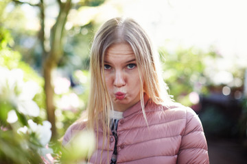 Fototapeta premium Portrait of beautiful blond girl posing in pink at garden