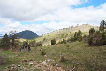 Fototapeta na wymiar Panoramic view with old rural wooden houses from the beautiful green plateau of Zabljak mountain to the snowy Durmitor mountain
