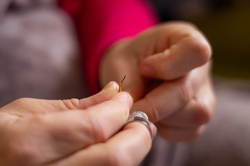 Obraz na płótnie Canvas Woman cutting and knotting a thread on a needle