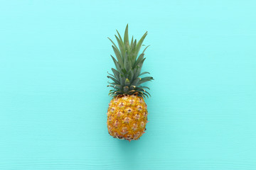 Ripe pineapple over blue wooden background. Beach and tropical theme. Top view