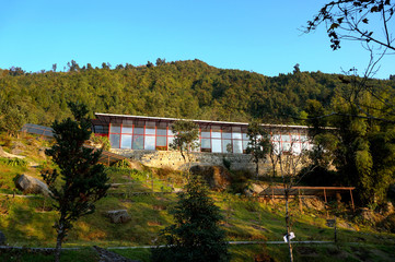 Fototapeta na wymiar Beautiful glass-built Plant house under blue sky in the hill forest at Gangtok