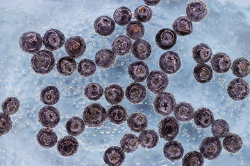 Ripe blueberry berries in blue water with air bubbles