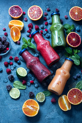 Colorful smoothies in bottles with berries and fruits