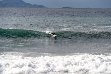 The surfer takes a wave, on a surfboard, slides along the wave, in the background of the mountain, Sorrento Italy