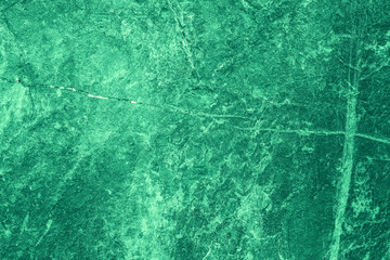 Vintage green background. Rough painted wall of emerald color. Imperfect plane of virid colored. Uneven old decorative toned backdrop of green tint. Texture of emerald hue. Ornamental stony surface.
