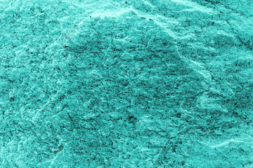 Vintage azure background. Rough painted wall of turquoise color. Imperfect plane of cyan colored. Uneven old decorative toned backdrop of aqzure tint. Texture of teal hue. Ornamental stony surface.
