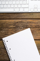 keyboard, note pad, on rustic wooden table background, top view