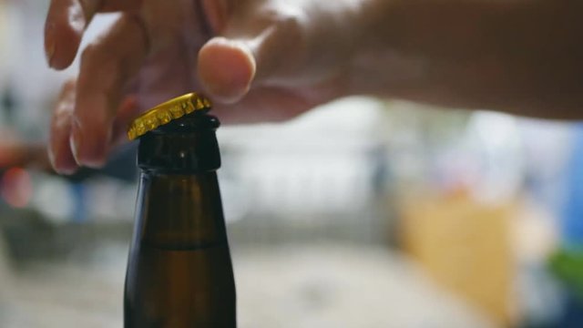 hand opens a bottle of beer