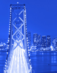 View of Bay Bridge across San Francisco Bay with lots of cars passing through in San Francisco at night.