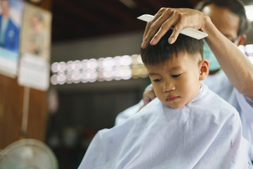 Asian boy getting hair cut by barber