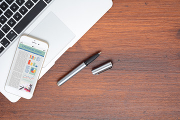Office desk table and smartphone phone with graphic information about company growth