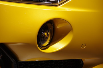 Yellow modern sports car round fog light close up view
