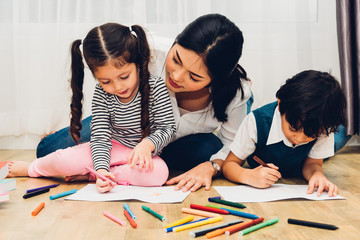 Happy child kid boy and girl son kindergarten drawing on peper teacher education with beautiful mother